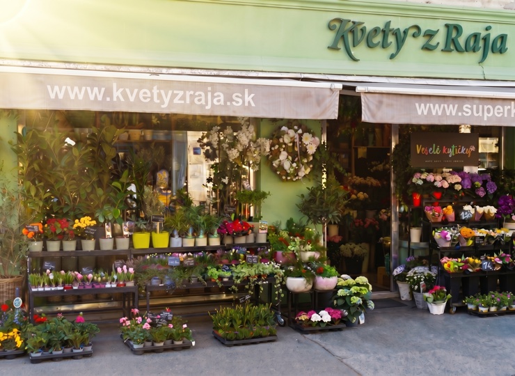 Priečelie predajne Kvety z Raja na Špitálskej 37 so zelenou markízou a stojanmi kvetov na chodníku